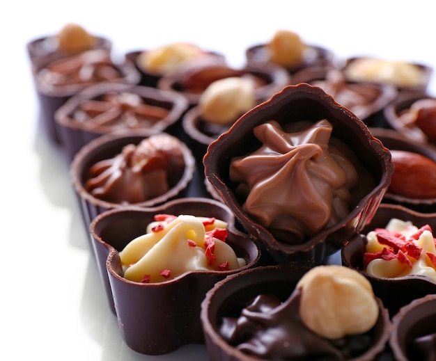 Delicious chocolate candies on white background, close up