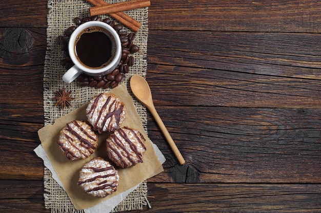 Delicious chocolate cookies and cup of hot coffee on old wooden table, top view. Space for text