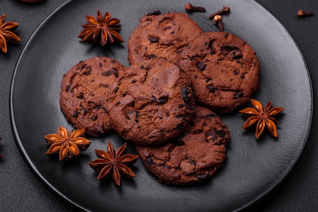 Delicious chocolate cookies with nuts on a black ceramic plate on a dark concrete background
