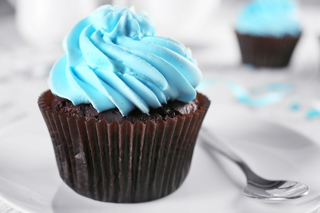 Delicious chocolate cupcake with blue cream on decorated wooden  table, close up