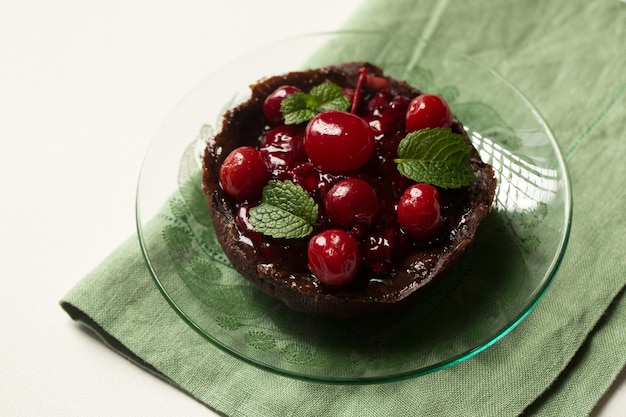 Photo delicious chocolate dessert with lingonberry jam cherries and mint on a transparent plate