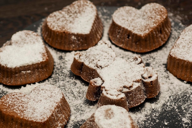 暗い木の背景に黒い皿に粉砂糖を入れたおいしいチョコレートマフィンやカップケーキ自家製ベーカリー