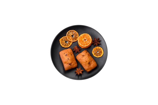 Delicious chocolate muffins and dried round shaped slices of bright orange color tangerine on a dark textural background