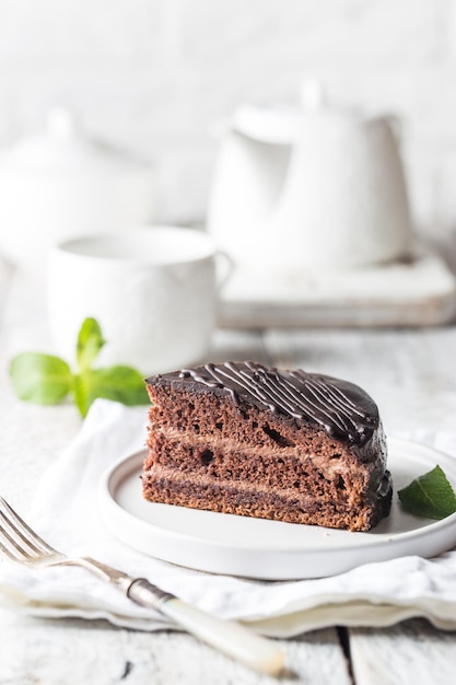 白い背景の上のプレート上のおいしいチョコレートプラハケーキ