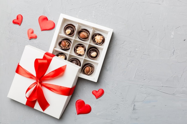 Foto deliziose praline di cioccolato in scatola rossa per san valentino. scatola di cioccolatini a forma di cuore vista dall'alto con spazio per la copia.