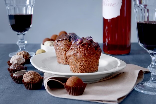 Delicious chocolate sweets and red wine on grey background