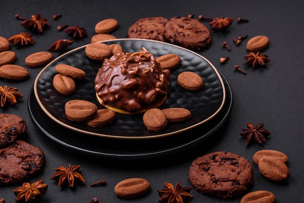 Delicious chocolate tart with nuts on a black ceramic plate on a dark concrete background