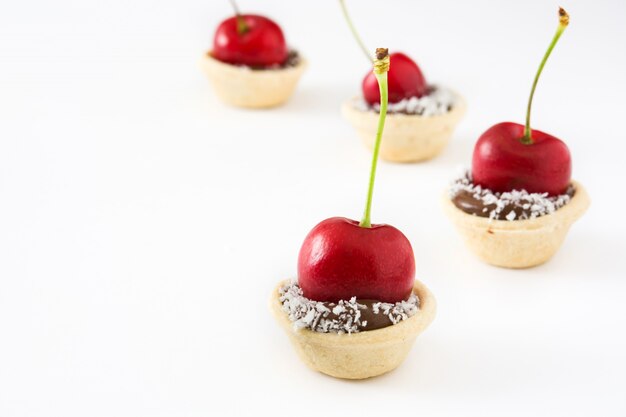 Delicious chocolate tartlets with one cherry and coconut isolated copy space