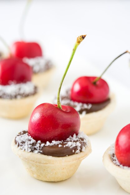 Delicious chocolate tartlets with one cherry and coconut isolated