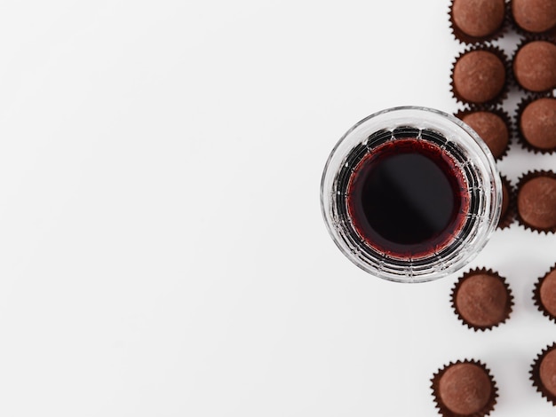 Delicious chocolate truffles and red wine on white background