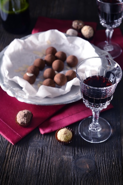 Delicious chocolate truffles and red wine on wooden background
