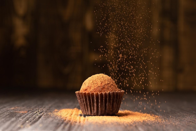 Delicious chocolate truffles sprinkled with cocoa on a black reflective background