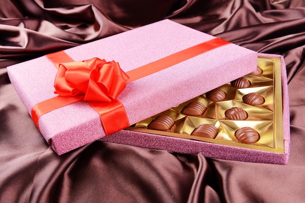 Delicious chocolates in box on brown background