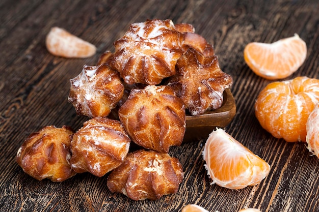 Delicious choux pastry with powdered sugar and delicious cream filling inside cake made of dough and milk filling on a wooden table