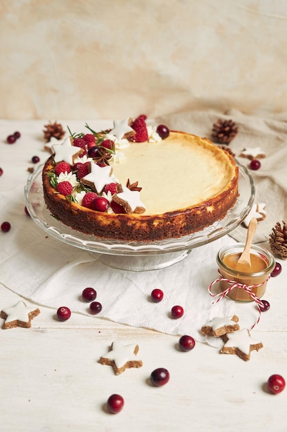 Deliziosa torta di formaggio di natale con mirtilli rossi e biscotti stelle su un tavolo bianco