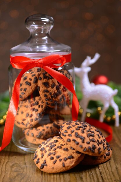 Delicious Christmas cookies in jar on table on brown background