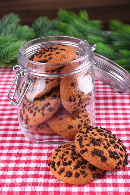 Delicious Christmas cookies in jar on table on wooden background