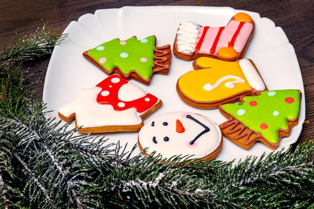 Delicious Christmas cookies in a plate near a Christmas tree branch