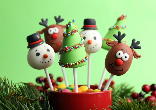 Photo delicious christmas themed cake pops on green background closeup