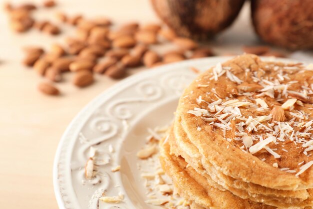 Delicious coconut pancakes decorated with almond shavings on table