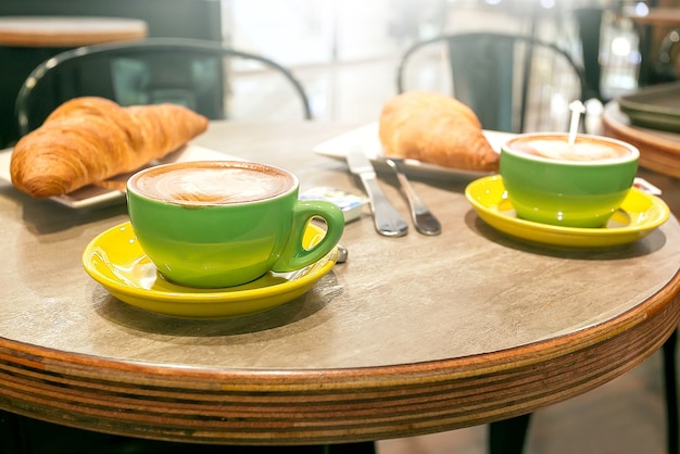 Delicious coffee with croissan on rustic wood table in the cafe.