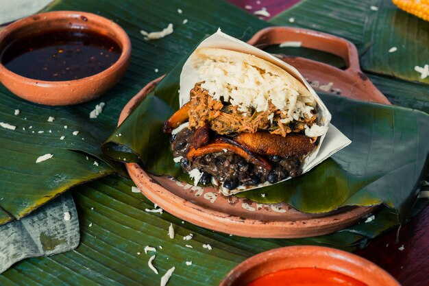 Delicious Colombian food with green banana leaves and salsa, stuffed arepas. Food.
