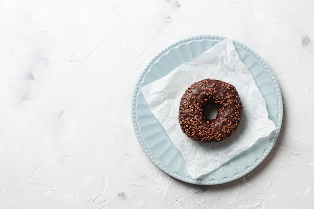 Delicious colorful donuts with sprinkles on stylish plate on white table with confetti, flat lay. Party concept. No diet. Candy bar at wedding reception. Purple and pink donuts