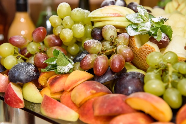 Delicious and colorful fruits with mint leaves on the plate close up