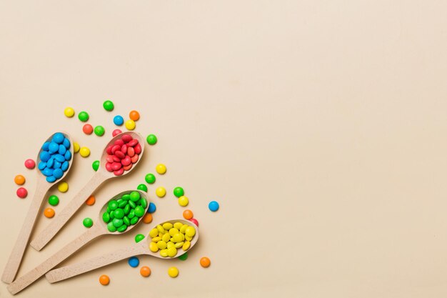 delicious colorful sweet candies on spoon on colored background Confectionery decor top view with copy space