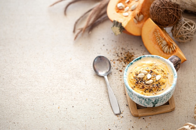 Delicious composition with pumpkin soup in a beautiful ceramic dish top view. Seasonal food.