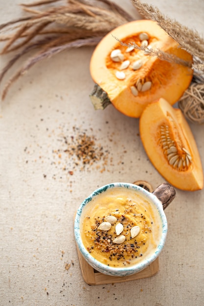 Delicious composition with pumpkin soup in a beautiful ceramic dish top view. Seasonal food.