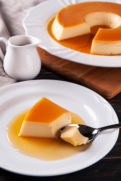 Delicious condensed milk pudding on white plate Someone scooping up a piece with a spoon