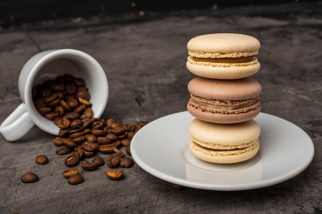 Вкусное печенье macarons на тарелке и в зернах кофе