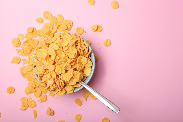 Photo delicious cornflakes in a plate against colored background