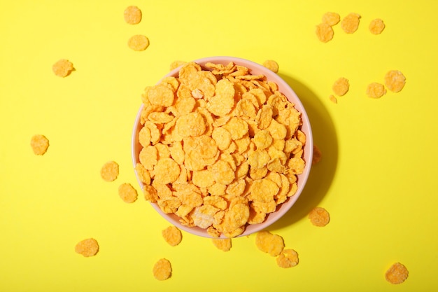 Delicious cornflakes in a plate against colored background