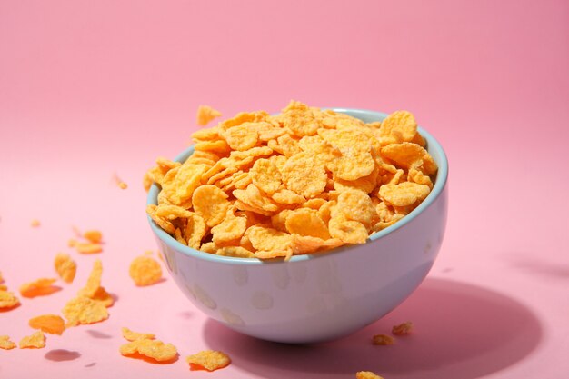 Delicious cornflakes in a plate against colored background