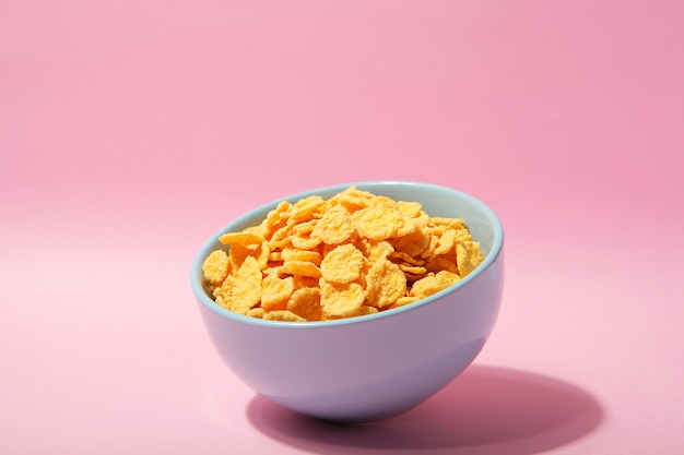 Photo delicious cornflakes in a plate against colored background