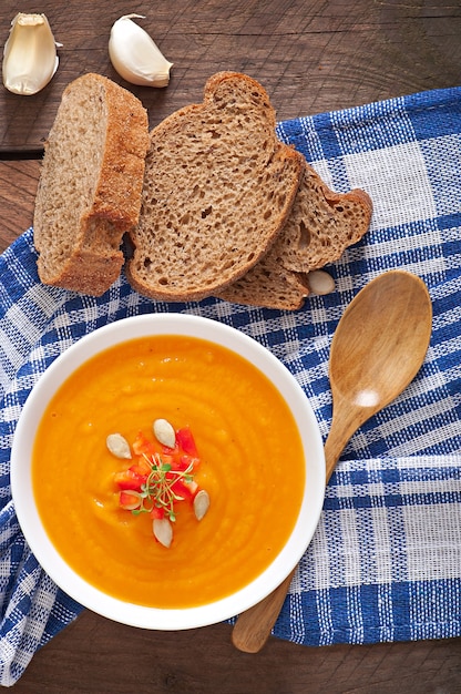 Crema deliziosa della minestra della zucca in una ciotola sulla tavola di legno