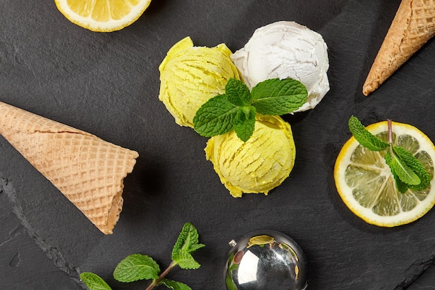 Delicious creamy and lemon ice cream decorated with mint served on a stone slate over a black backgr