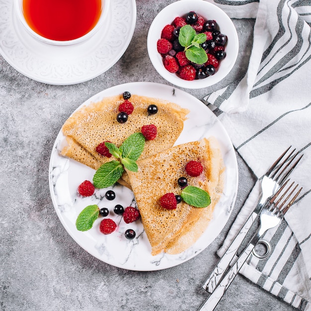 Фото Вкусный завтрак блинчики на фоне серого бетонного стола. блинчики с ягодами