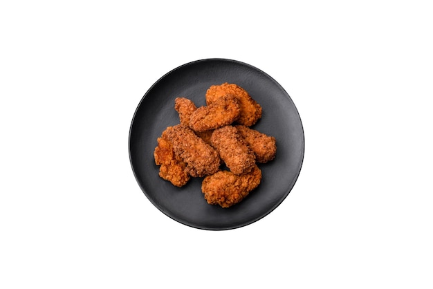 Delicious crispy breaded chicken wings grilled with spices and herbs on a dark concrete background