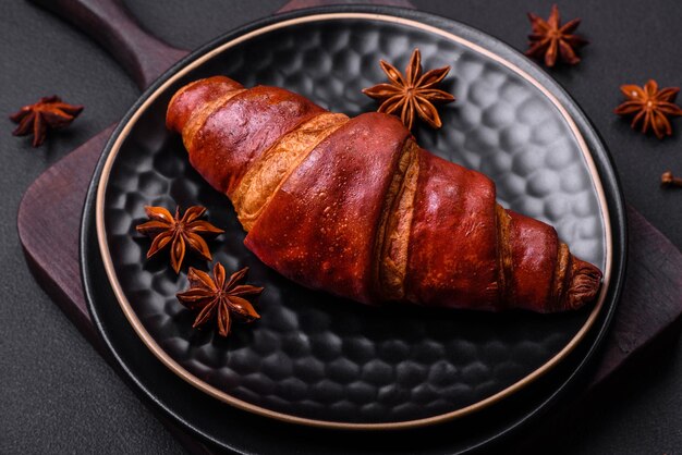 Delicious crispy croissant with chocolate on a black ceramic plate