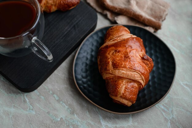 Delicious crispy croissant with chocolate with a cup of invigorating coffee on a light concrete background Delicious nutritious breakfast