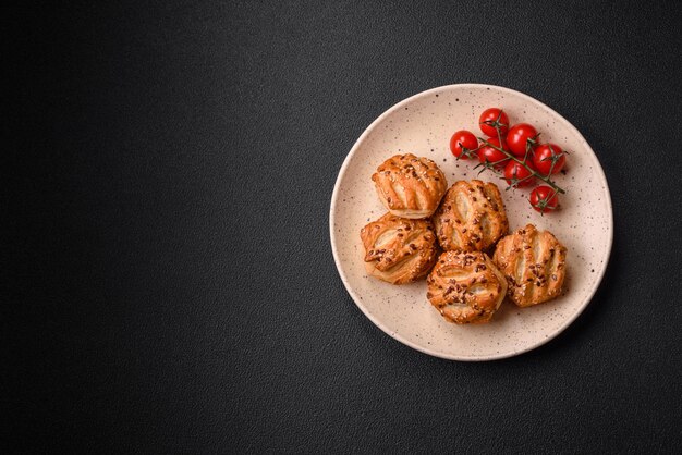 Photo delicious crispy mini puffs with sausage or meat with salt thyme and sesame on a dark concrete background
