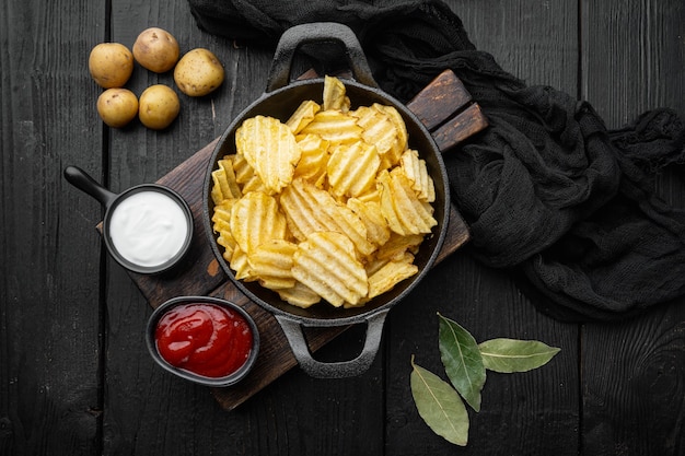 검은 나무 테이블에 맛있는 바삭한 감자 칩 세트, 평면도 평면 누워