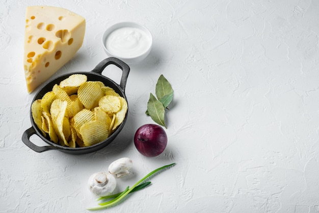 Delicious crispy potato chips set with Cheese and Onion, with dipping sauces tomato dip sour cream, on white stone  surface, with copy space for text