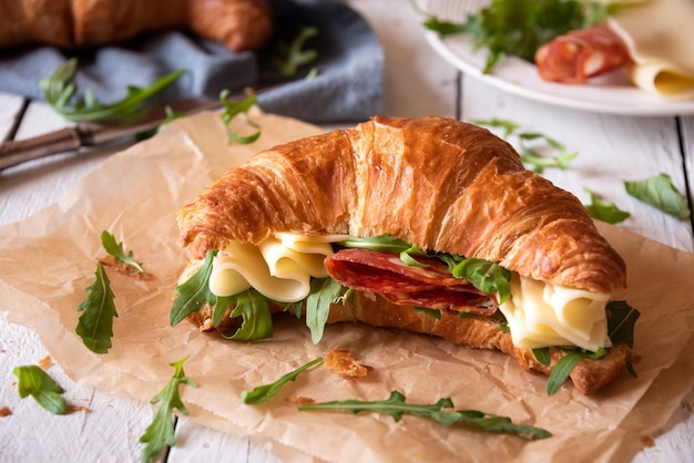 Delicious croissant sandwich with cheese and arugula