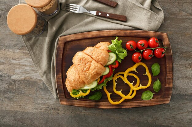 Delicious croissant sandwich on wooden board