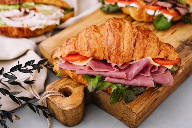 Delicious croissant sandwich on wooden board