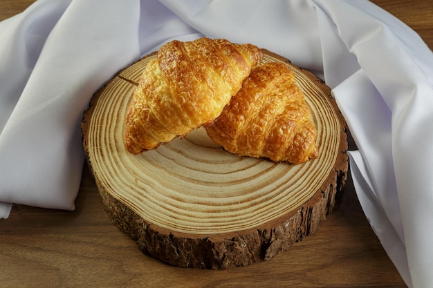 Foto deliziosi croissant sul tronco di legno con asciugamano bianco intorno